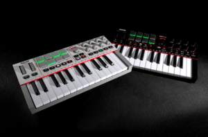 Two compact MIDI keyboard controllers with white and black keys and control pads rest on a black leather surface—perfect gift ideas for musicians who value portability and versatility in their setup.